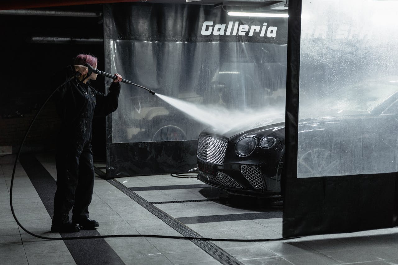 Crafting Captivating Headlines: Your awesome post title goes here A woman power washing a luxury car in an indoor garage setting, showcasing car wash service.